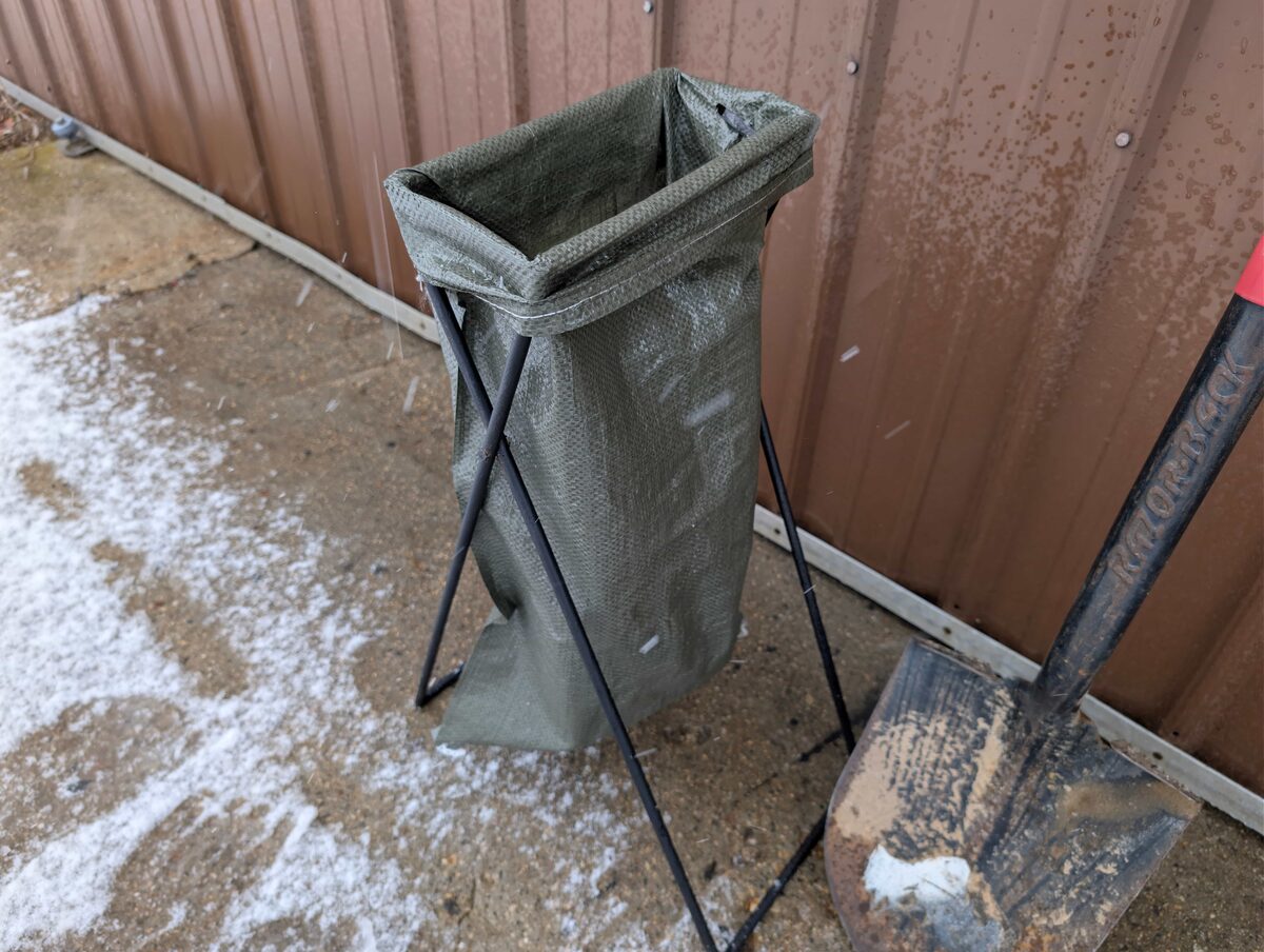 The stand holding a bag open at shovel height