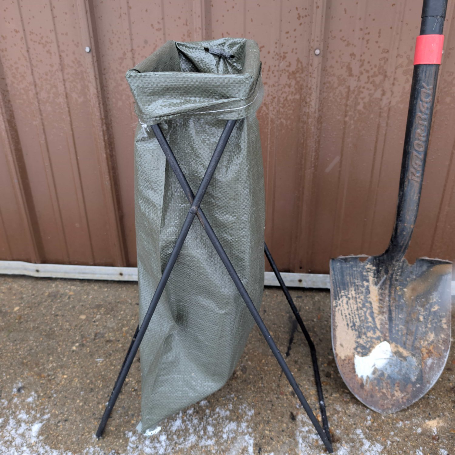 Tuftler sandbag stand holding a bag open beside a shovel