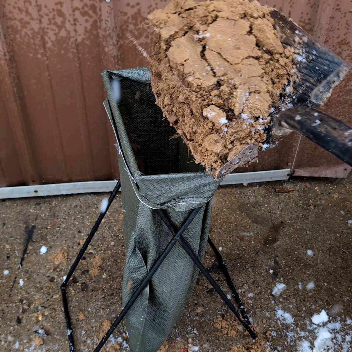 Shovelling dirt into the bag with both hands free